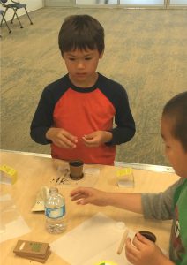 Young boy waits for his turn to water his newly planted bush beans at Coquitlam Library's Plant a Seed READ!