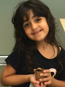 Young girl proudly smiling with her mini planting kit at Coquitlam Library's Plant a Seed READ! event.