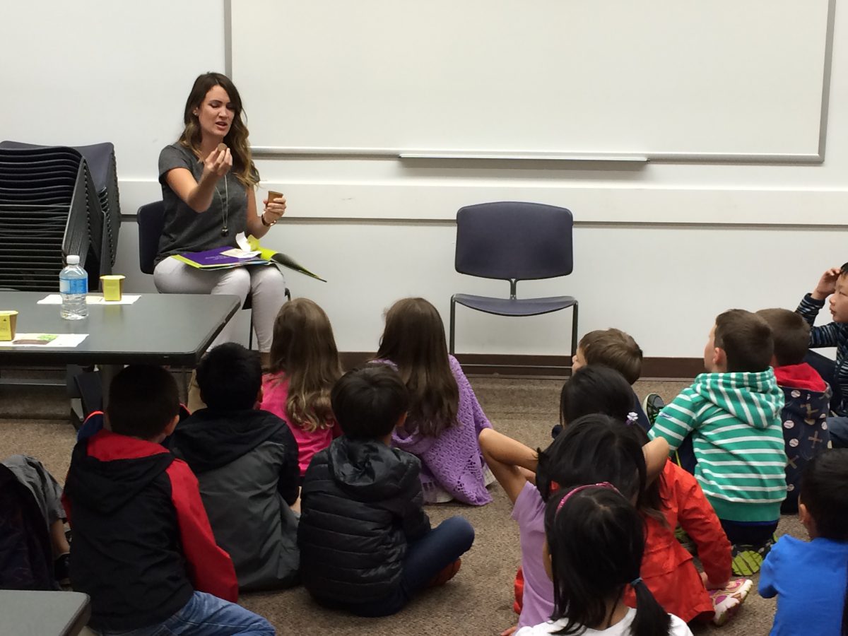 Teacher holding a soil wafer to show how to plant at Coquitlam Library's Plant a Seed READ!