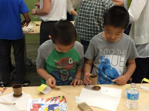 Young Asian boys planting bush beans seeds at Coquitlam Library's Plant a Seed READ! event.