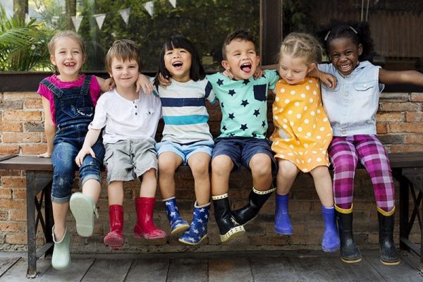 Kindergarten kids friends arm around sitting smiling
